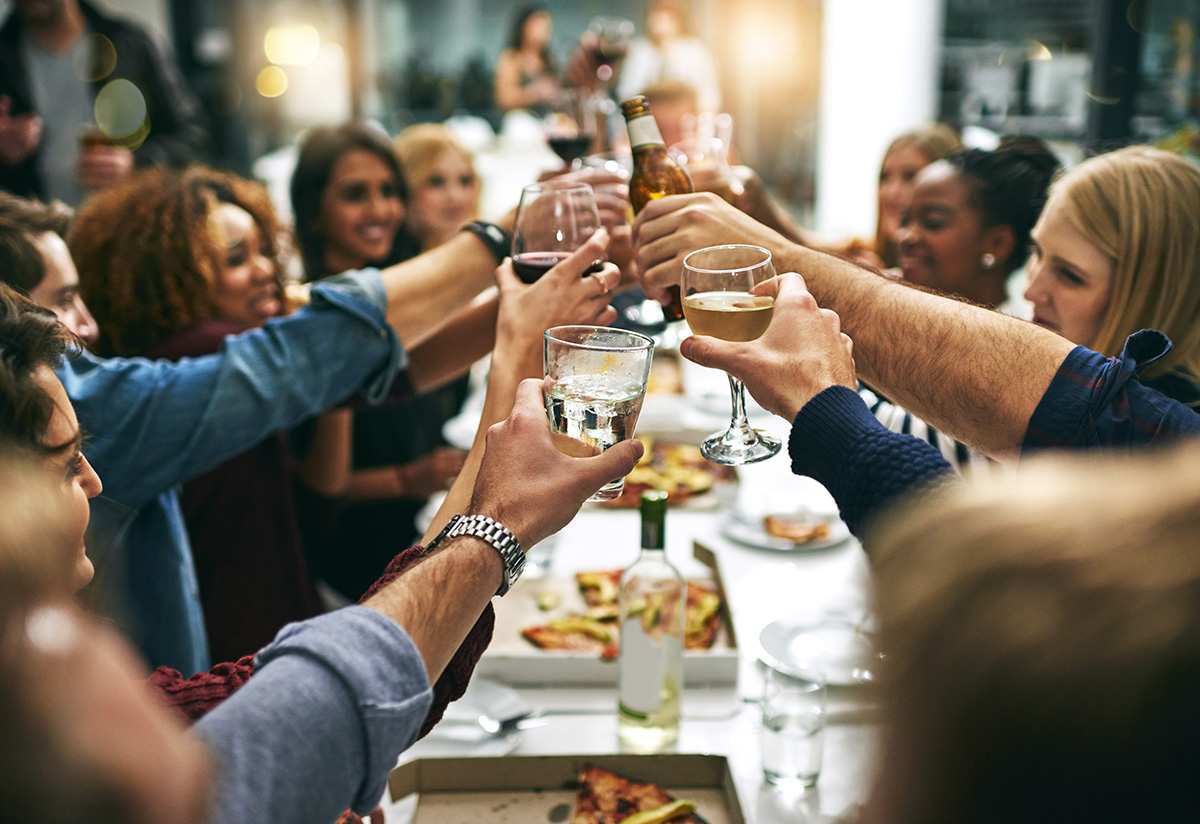 large group toasting with wine and beer at a table